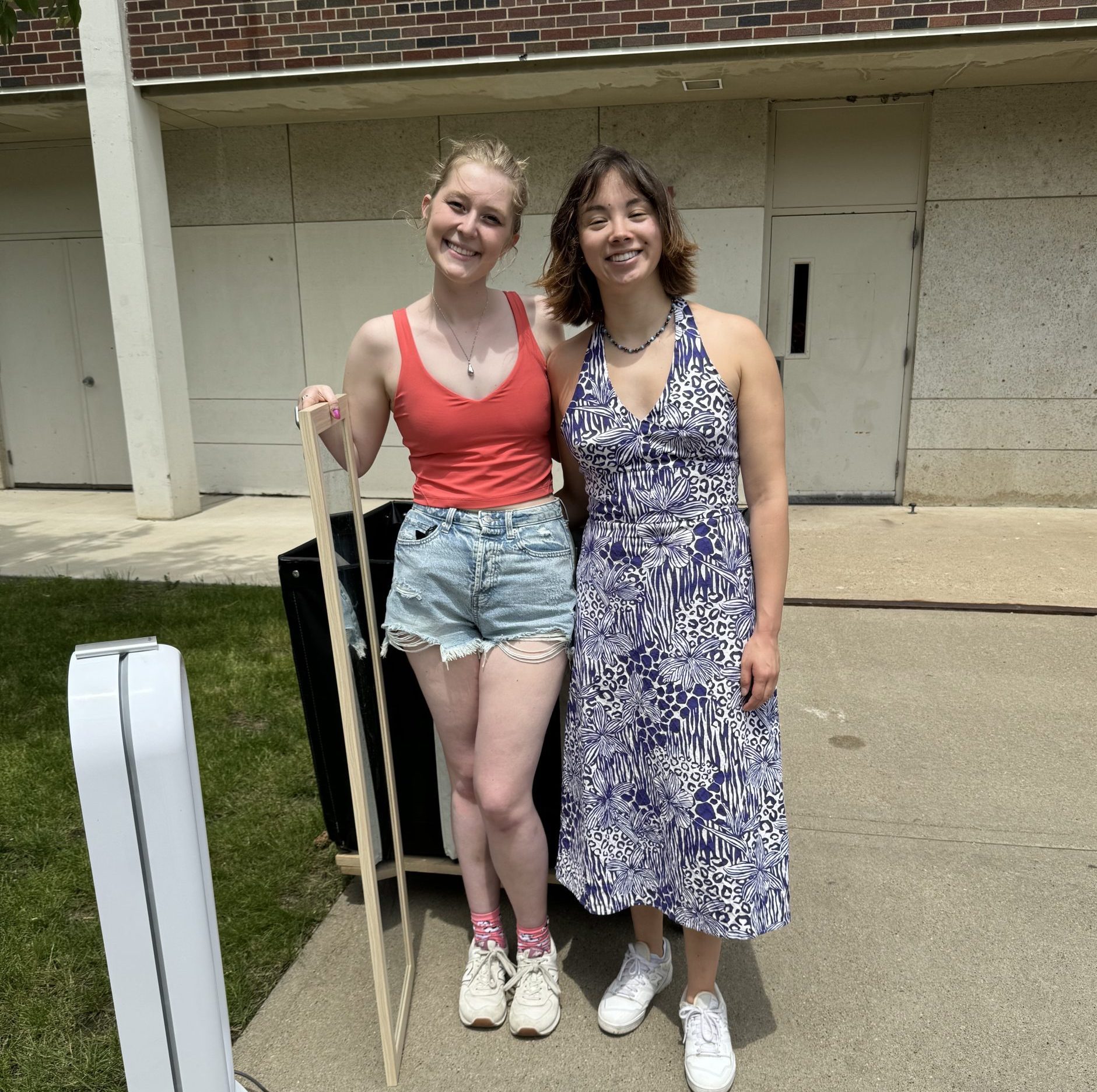 Two girls smiling and holding a mirror