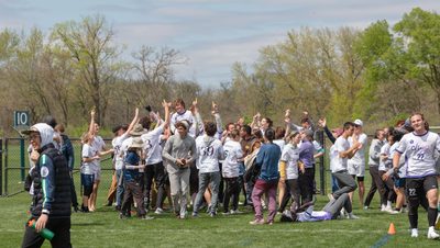 A group of Carleton frisbee players celebrate together.
