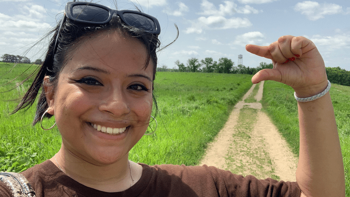I student standing on a walking trail in front of a water tower.