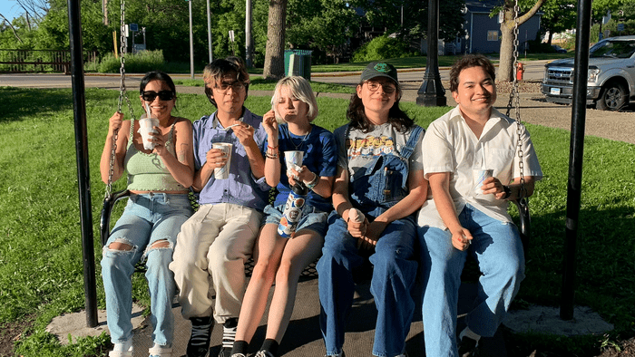 5 students sitting on a hanging bench and eating ice cream