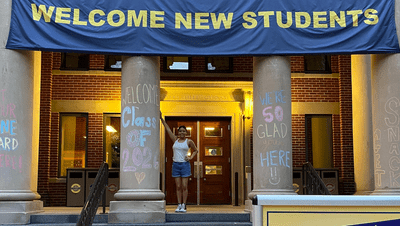 a student underneath a "welcome new students" banner