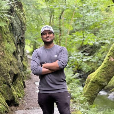 A student stands on a hiking trail that leads through a forest