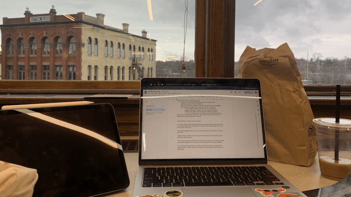 A laptop with the view of an old building in window behind it.