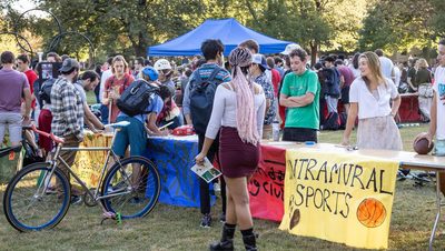Carleton students visiting the Activities Fair on the bald spot. One table's banner reads, "Intramural Sports."