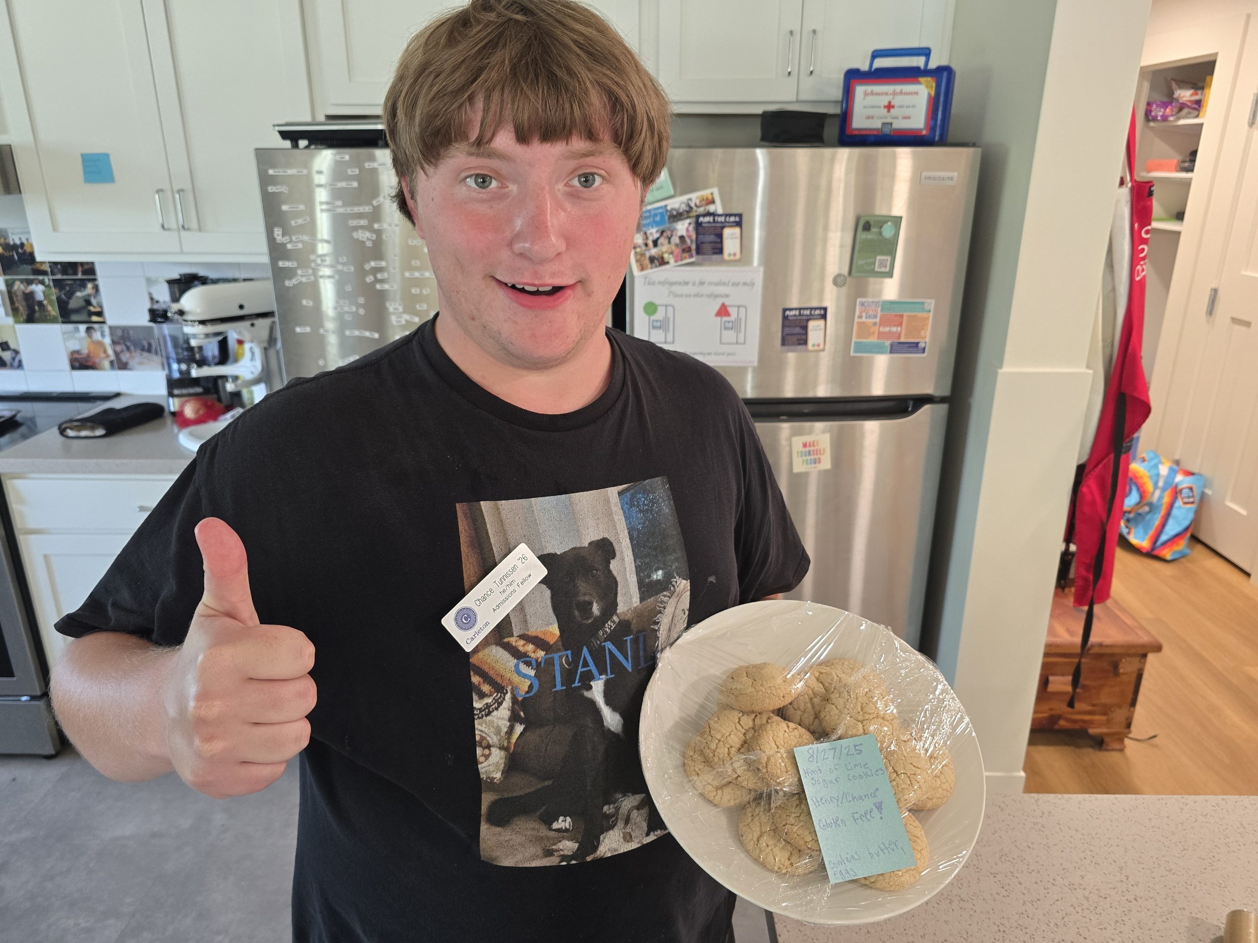 a student giving a thumbs up and holding a plate of cookies