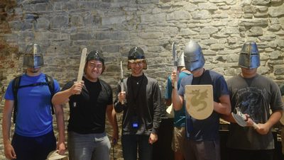 Students pose as knights, wearing helmets and brandishing wooden swords