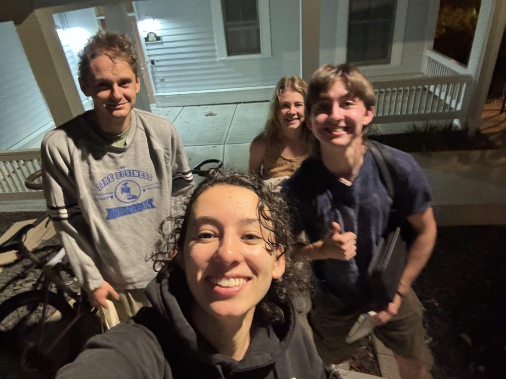 group of smiling students outside a townhouse