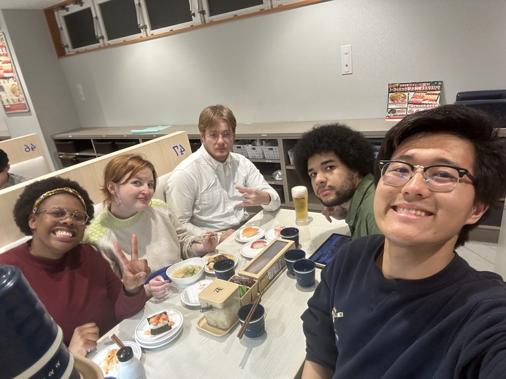 A group of TAs smiling while eating sushi 