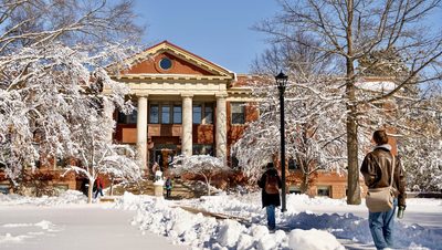 Students walk around campus on a snowy afternoon