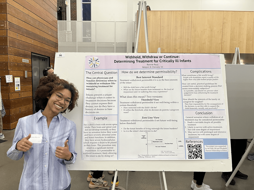 Student poses in front of their poster