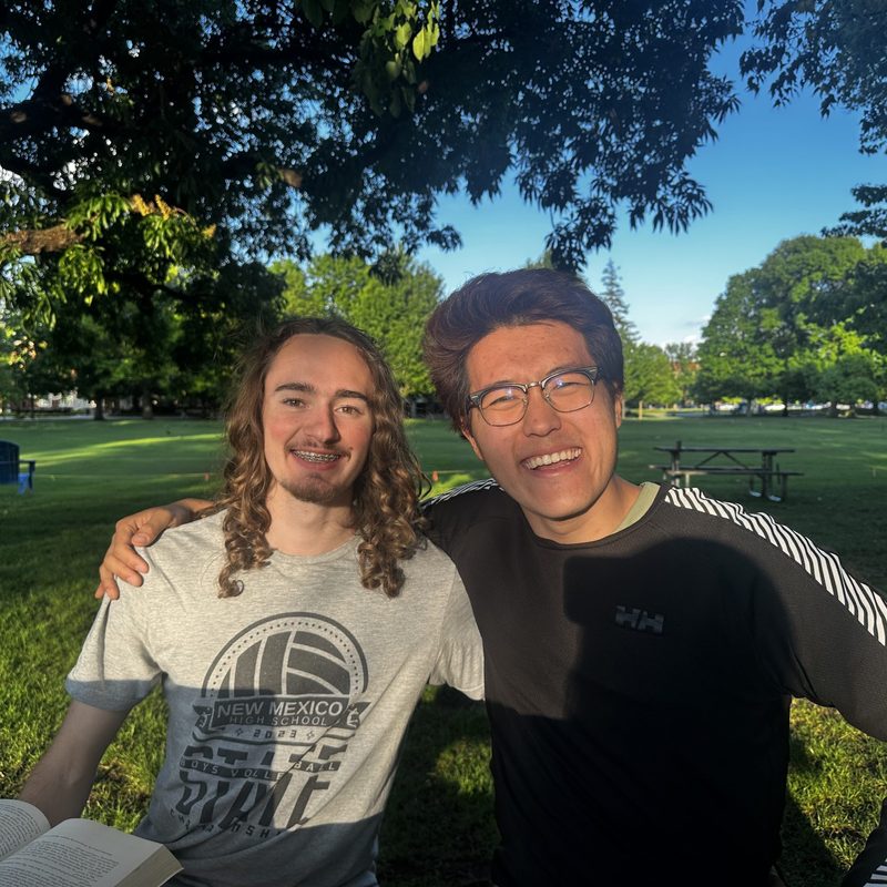 Two friends smiling for a photo on a large field