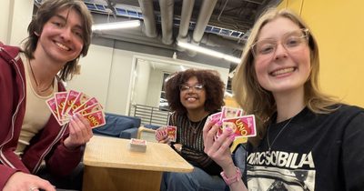 three students smiling with uno