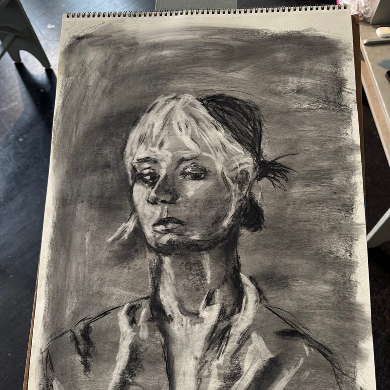A charcoal drawing of a subject from the torso up looking off to the side