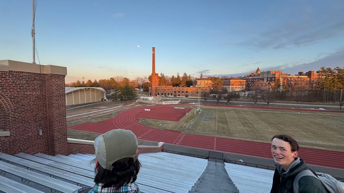 A view of campus from the top of stadium stairs with two people smiling and looking at the view