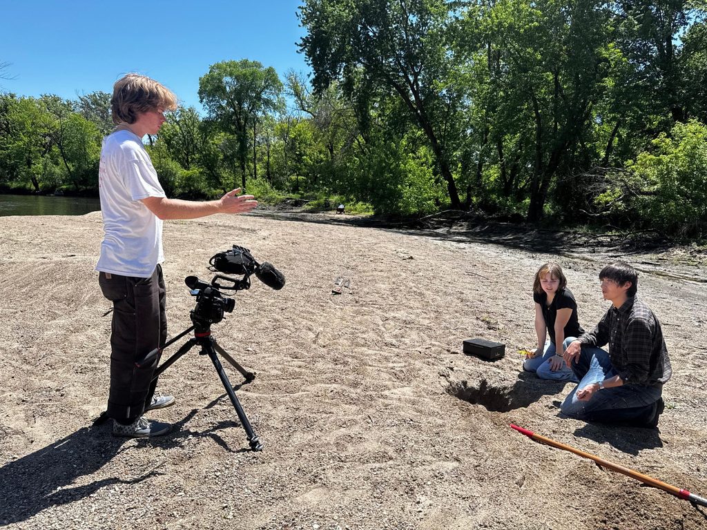 two students in front of a camera with a student directing them