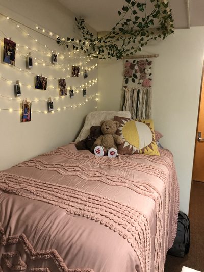 A dorm room with pink bedding and fairy lights