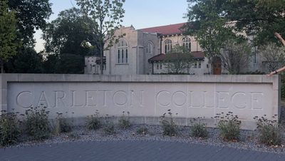 girl posing with Carleton sign