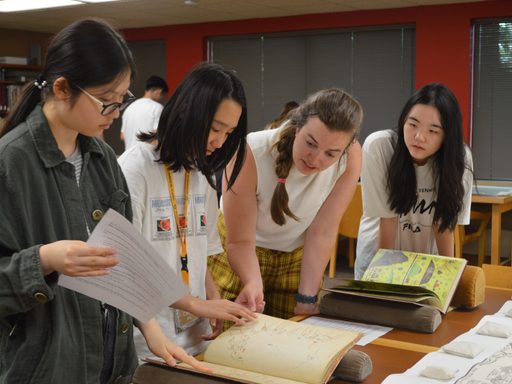 Students and a professor looking at books in the library archives