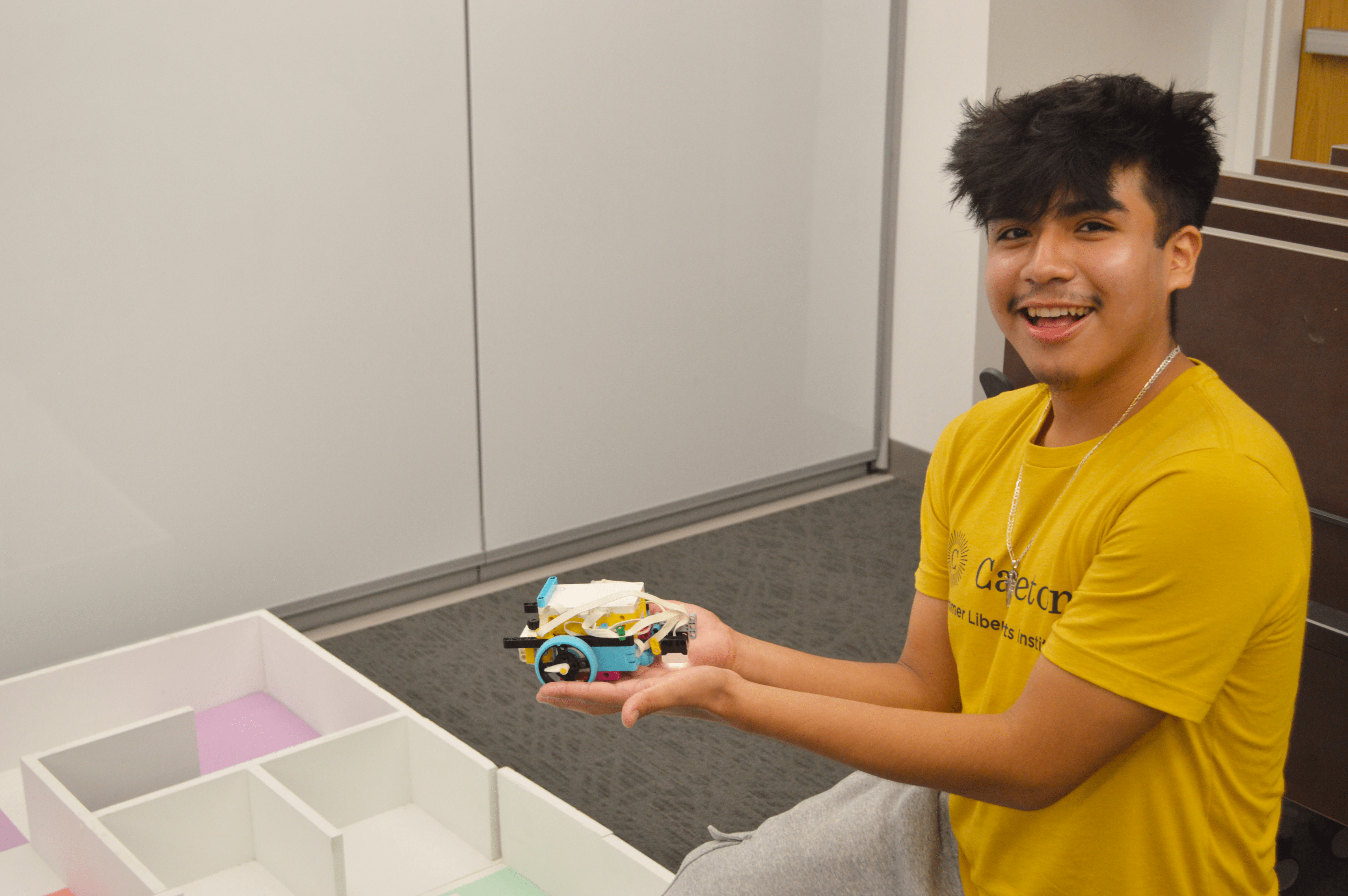 A SLAI student holds up a Lego robot.