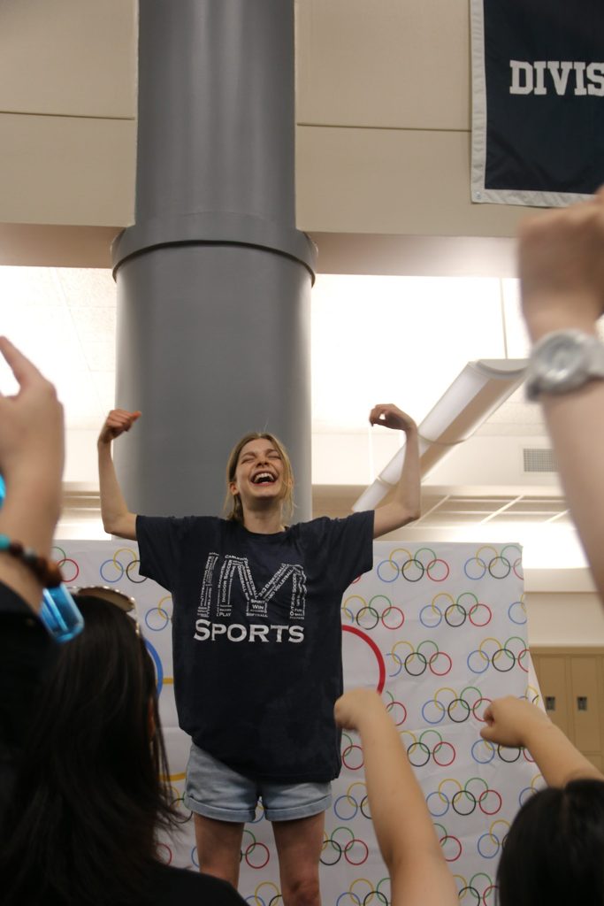 A student triumphantly raises her arms up in a sign of victory.