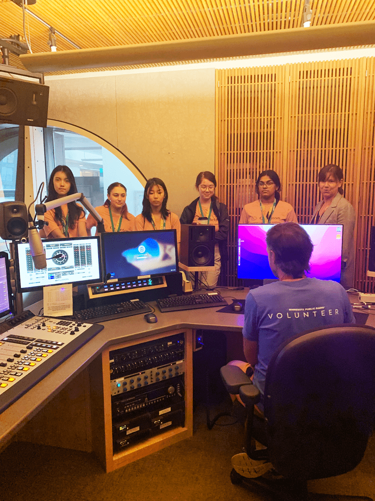 A group of five SLAI students visiting a radio control desk with a tour guide.