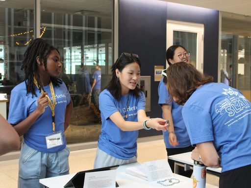 A student holds up an artifact while another person examines it. The student holding the artifact is providing an explination of the item.