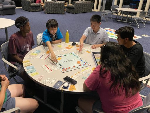 Students play monopoly game at table
