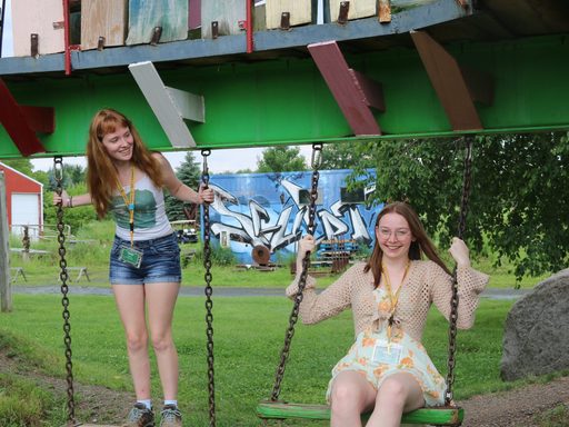 Two students swing and smile.
