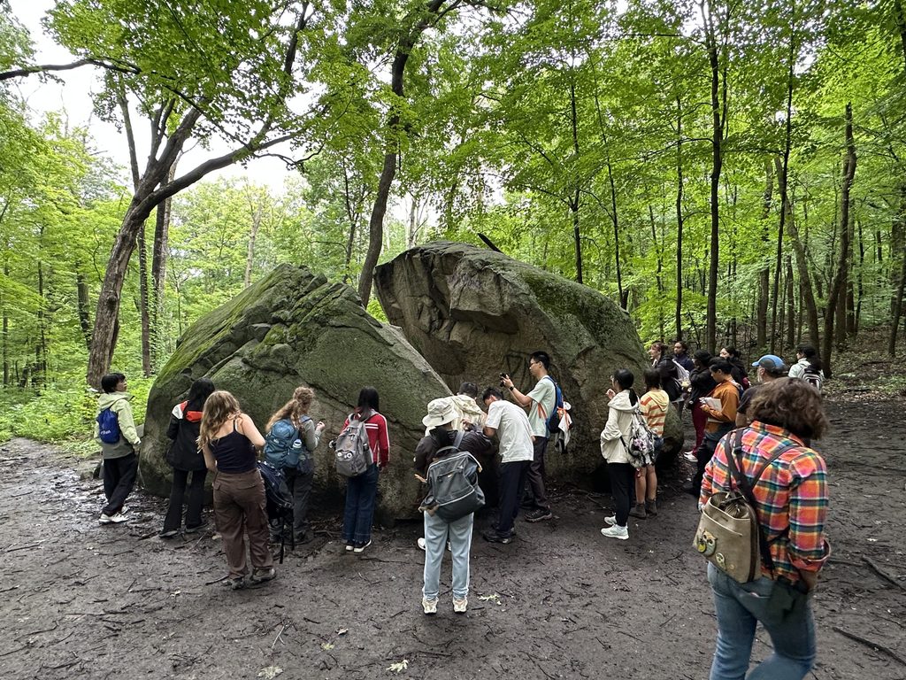 A far shot of students gathered around a large rock in Interstate Park, looking at it up close