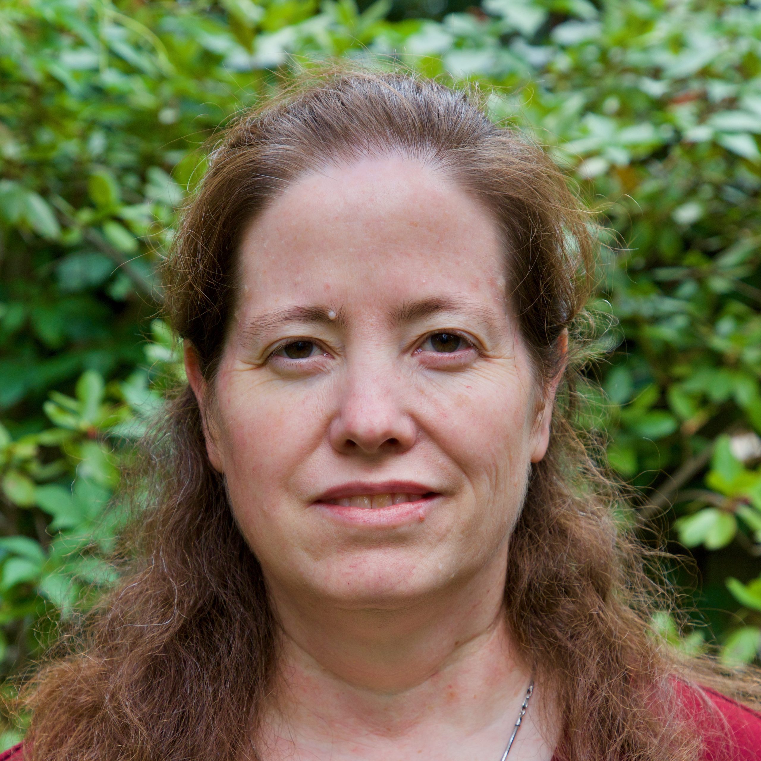 Professor Susan Fox in front of a blurred leafy background. 