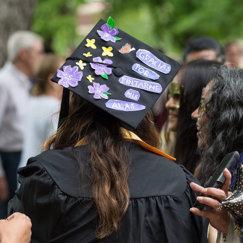 a student during commencement wearing a decorated graduation cap.