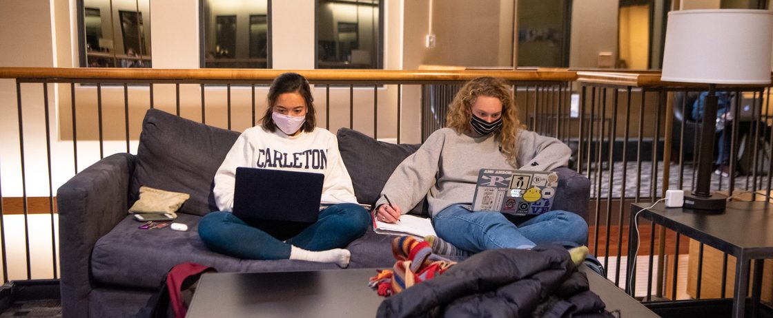 Two masked students on a couch in Sayles