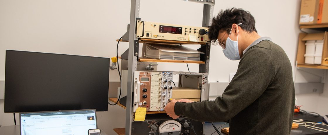 A masked student works in a physics lab