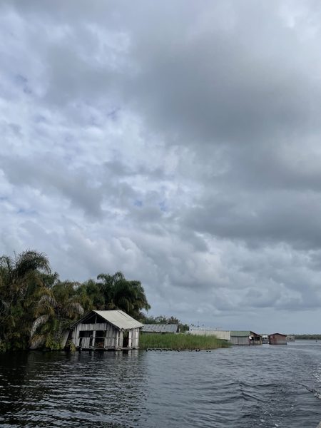 A stilt house sitting by the water, dark clouds hang overhead
