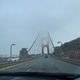 A view of the Golden Gate Bridge from the road of the bridge on a foggy, cloudy day such that the top of the bridge fades off into the fog.