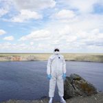 student standing in safety nuclear suit in front of body of water