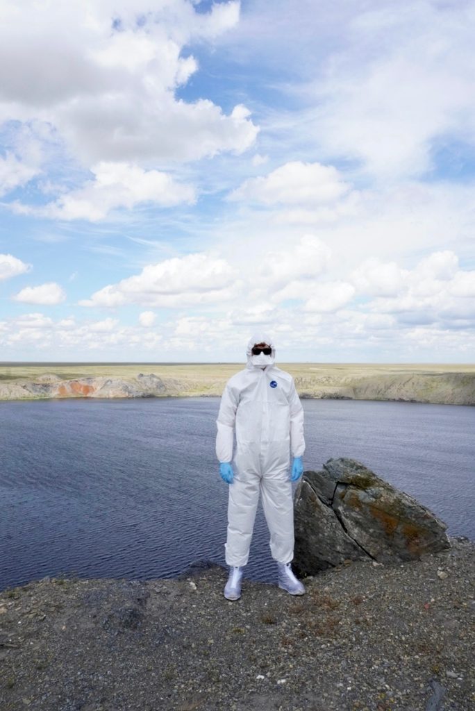 Harrison in radiation suit by lake