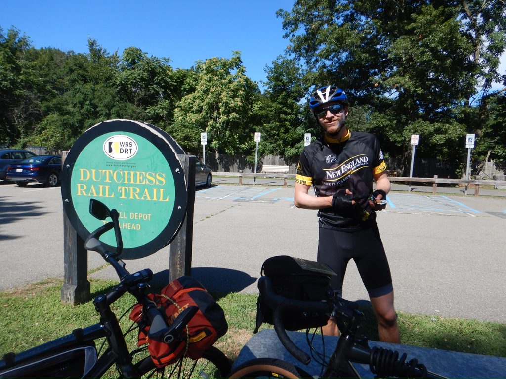 Person standing by bike next to Dutchess Rail Trail sign