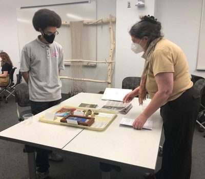 Student and Professor looking at artifacts.