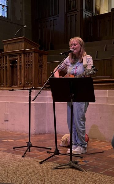 Carleton singing with guitar at National Coming Out Day Service