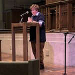 Student giving a talk at a podium at National Coming Out Day Service