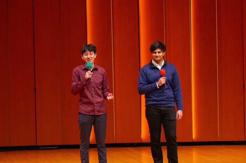 Two students on stage, each with a mic