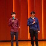Two students on stage, each with a mic