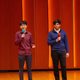 Two students on stage, each with a mic