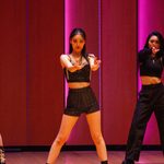 Two students on stage dancing with legs spread and arms out front