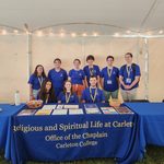 9 Chaplain's Associates posing behing the Office of the Chaplain's table at the NSW Resource Fair