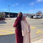 Two students posing back to back for picture on Eid