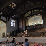 Marc Anderson leading Sound Bath Mediation from the stage, participants seated on the floor below