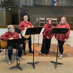 Associate Chaplains and Chaplain's Office Coordinator pose for a picture with guitars and music stands.