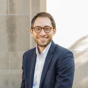 Rev Schuyler Vogel in a blue suit jacket, grey pants and brown glasses